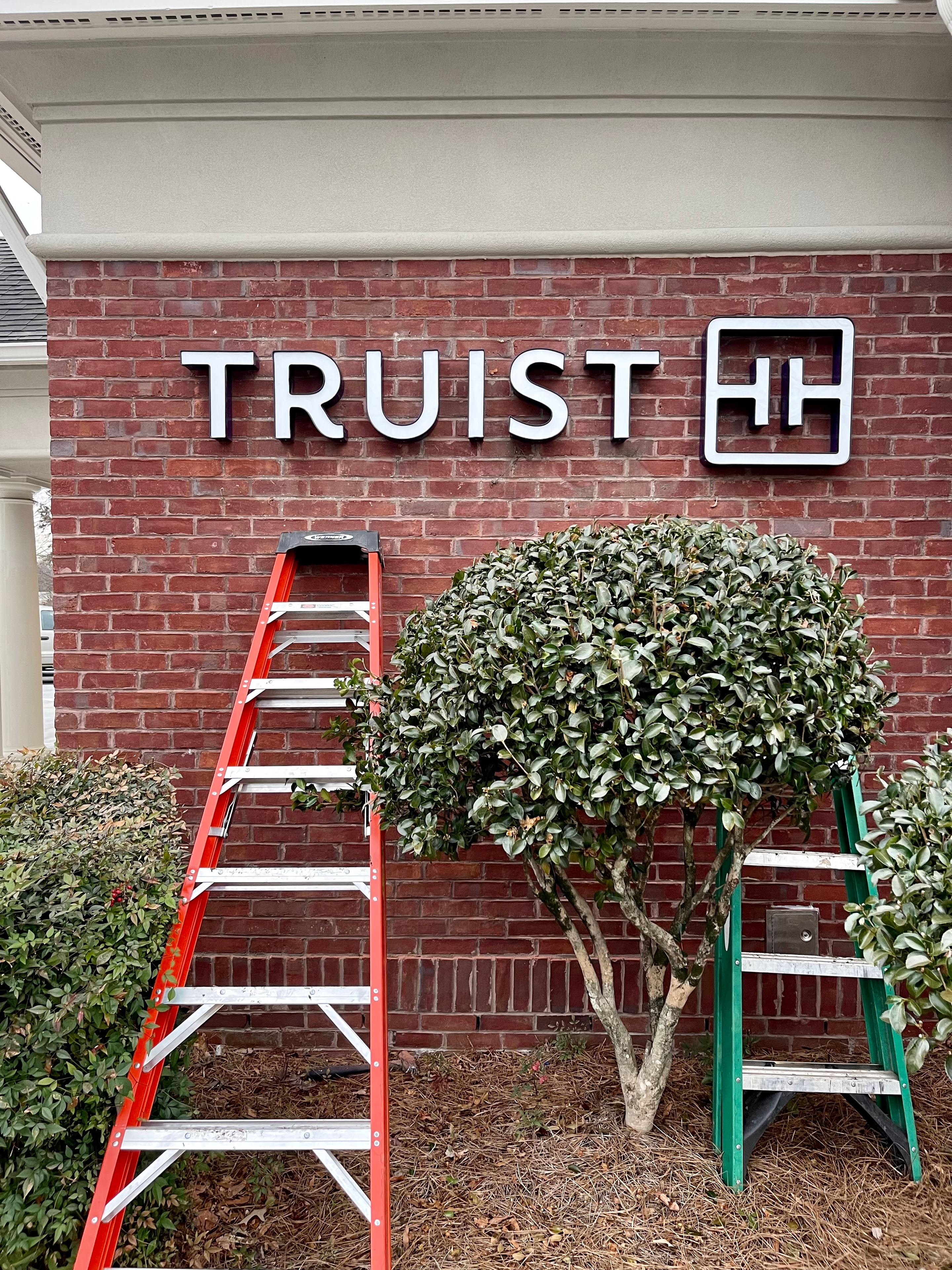 SOC crew installing signage at Truist Bank storefront with ladders